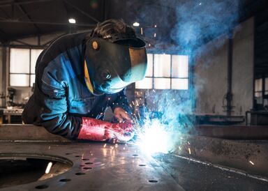Ein Mitarbeiter von F&K Metall führt präzise Schweißarbeiten an Metallteilen durch, um stabile und hochwertige Verbindungen zu schaffen.